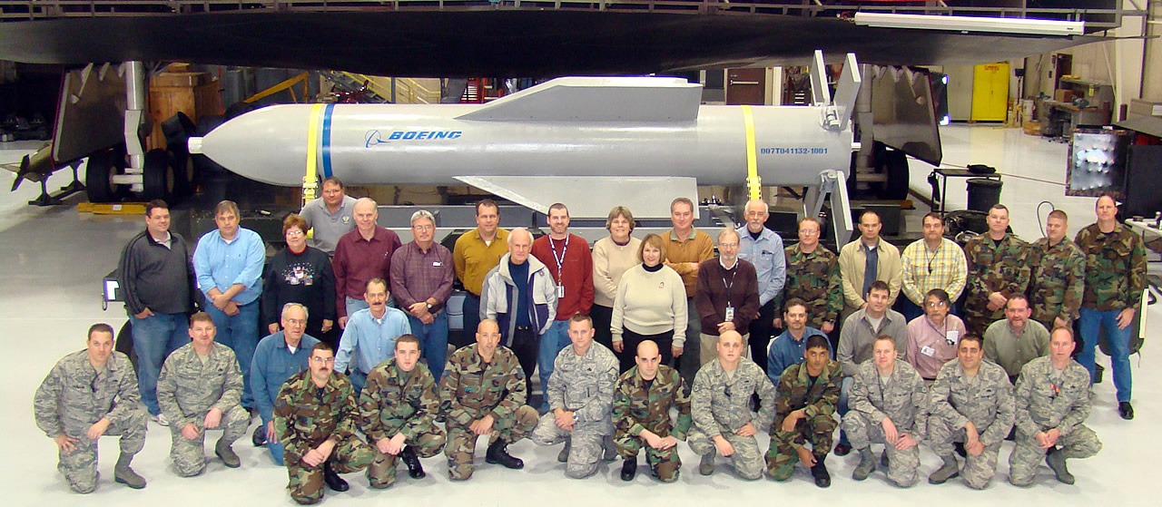 Group photo of personnel with a large bomb.