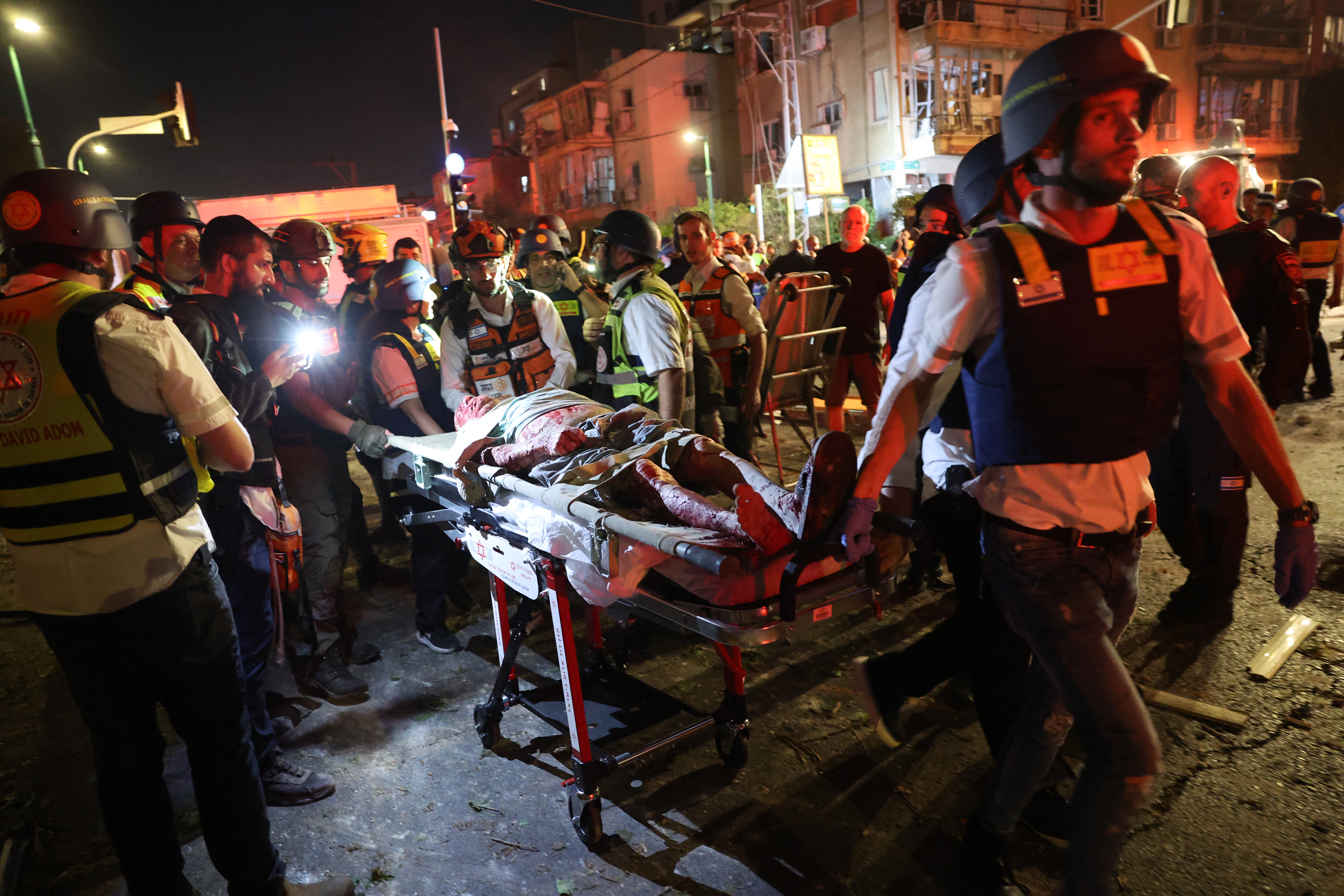 First responders carry an injured man away from the site a missile hit in Ramat Gan. 