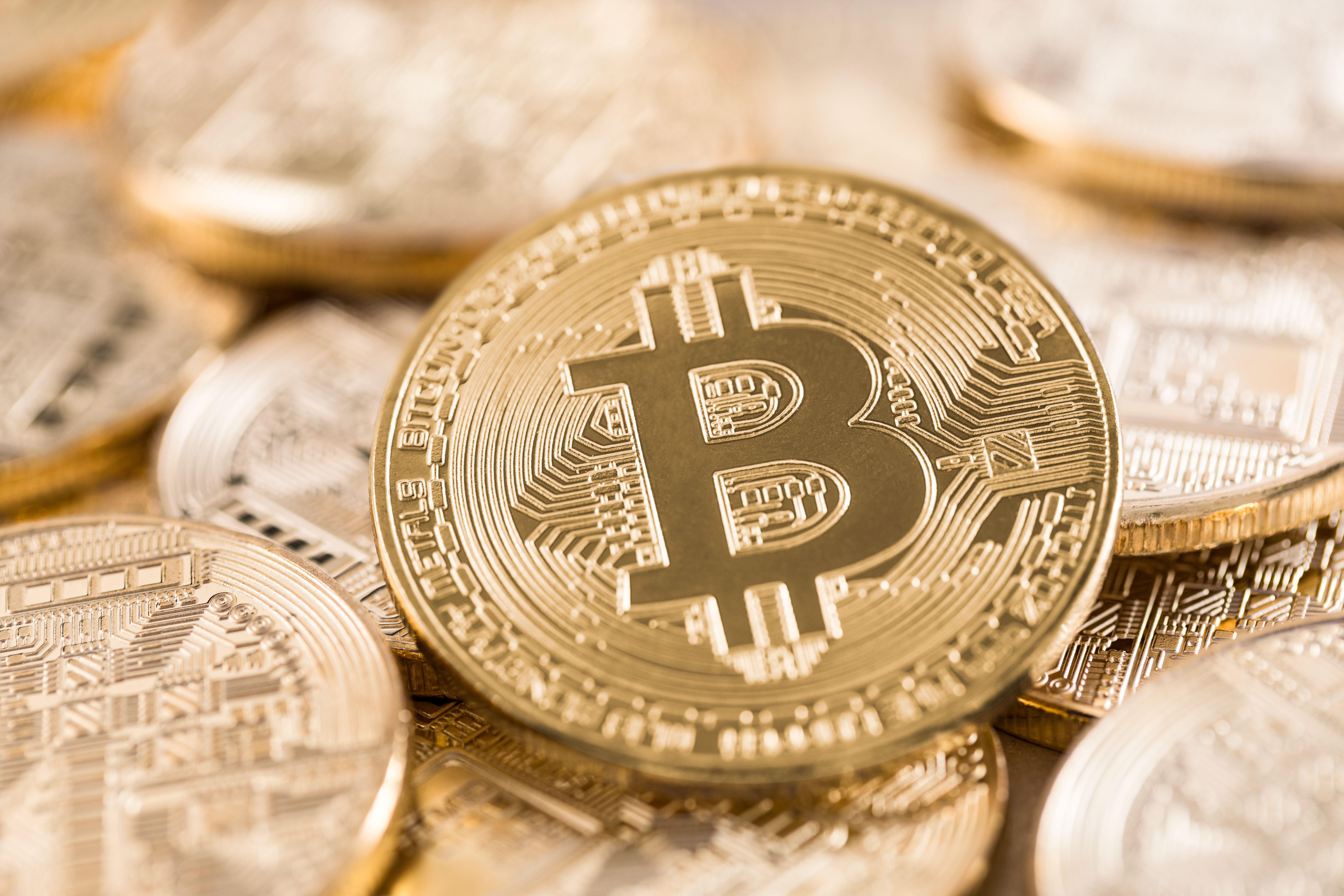 Close-up of a gold Bitcoin coin among other coins.