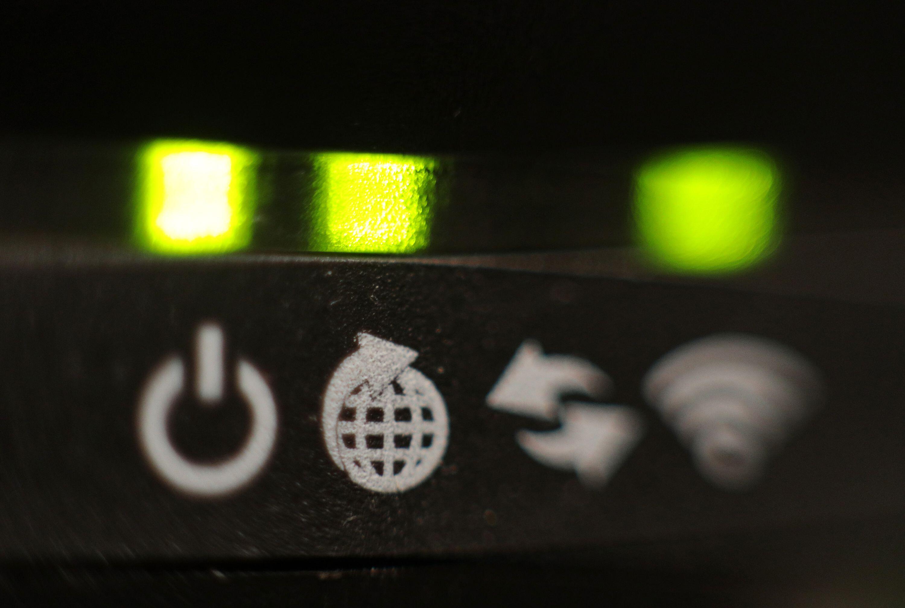 Close-up of a broadband router's illuminated lights and indicator symbols.