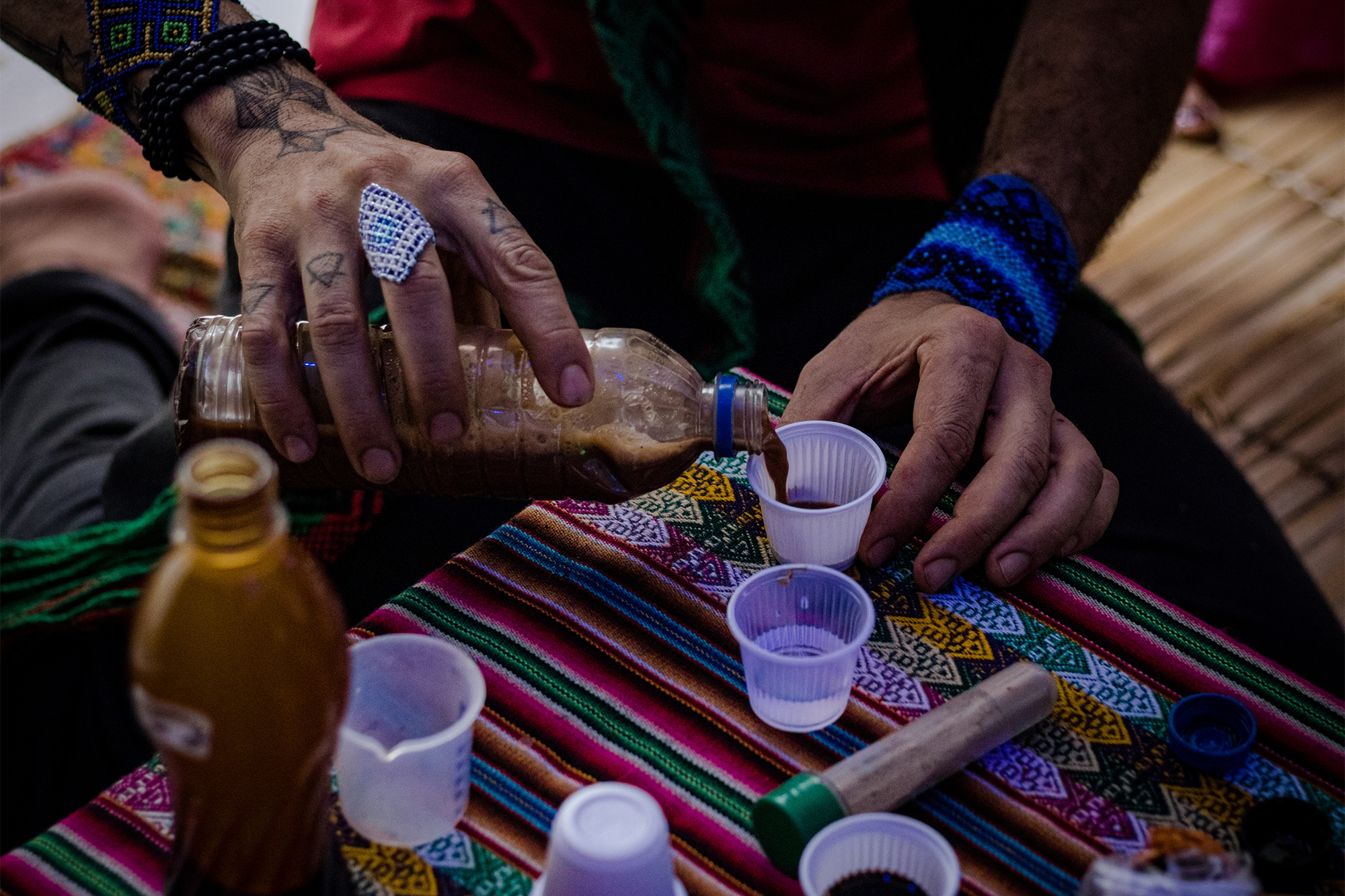 Person pouring psychedelic tea into small cups.