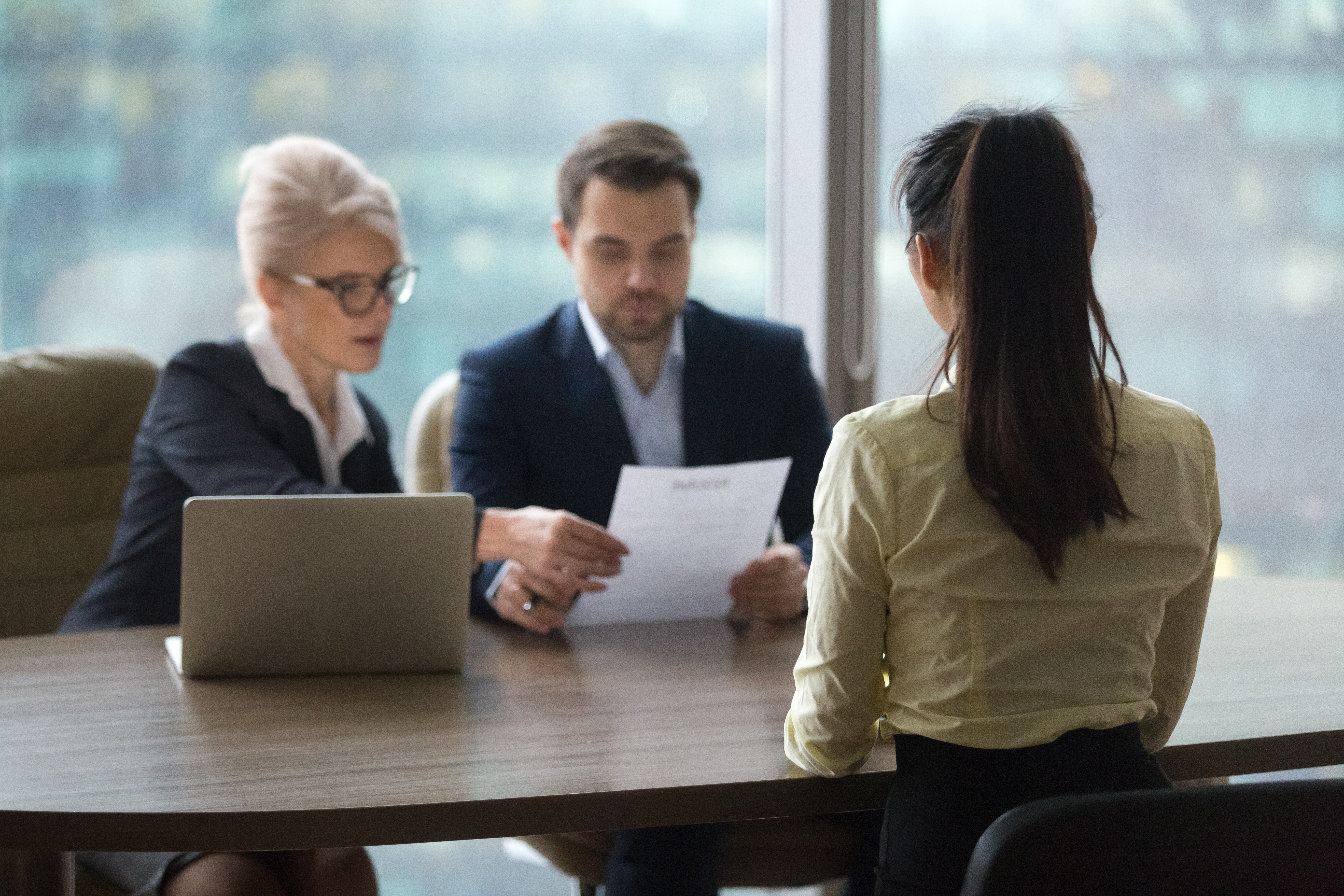 Job candidate sitting at a table during an interview with two interviewers.