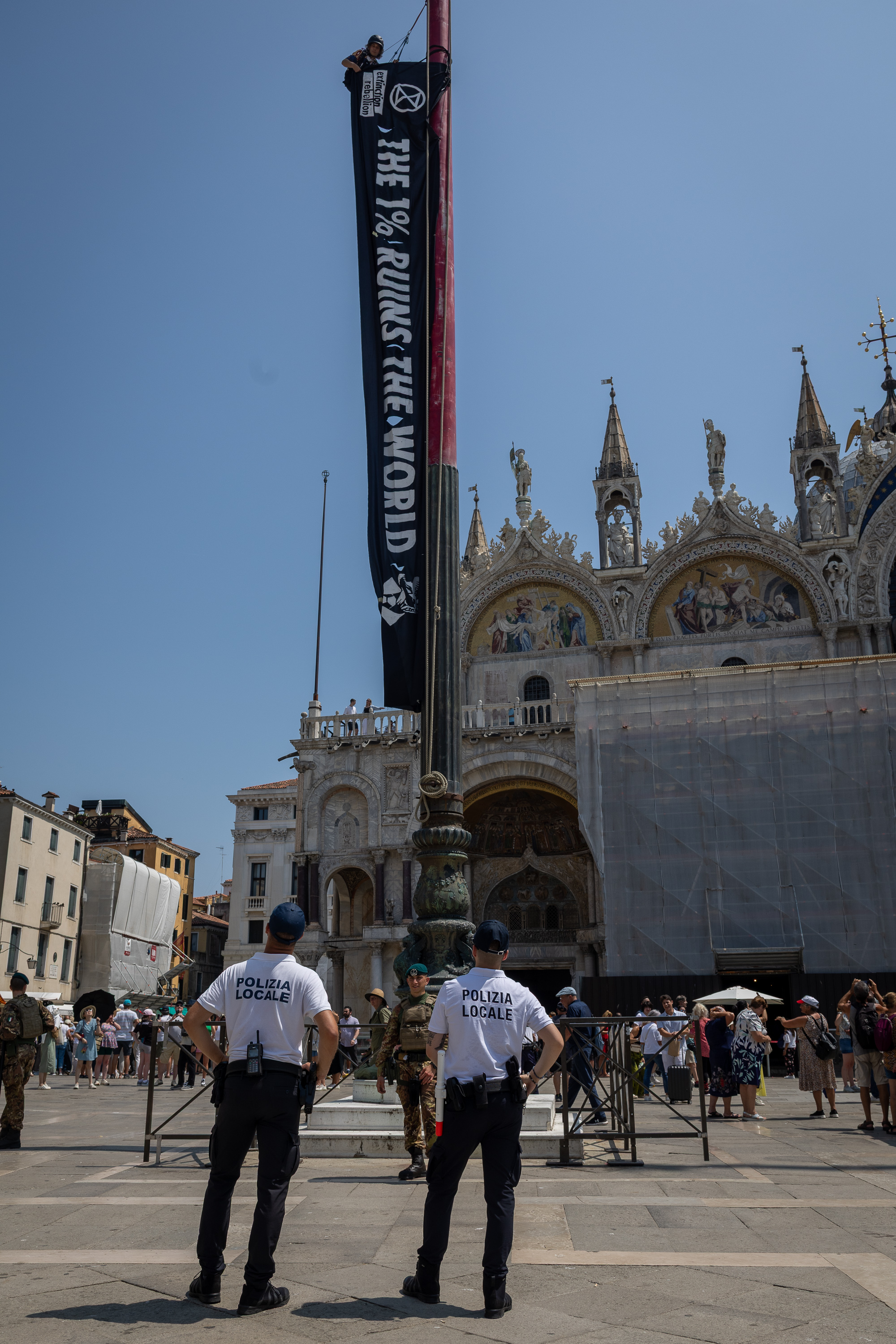 Protestor unfurls banner reading “The 1% ruins the world” in Venice.
