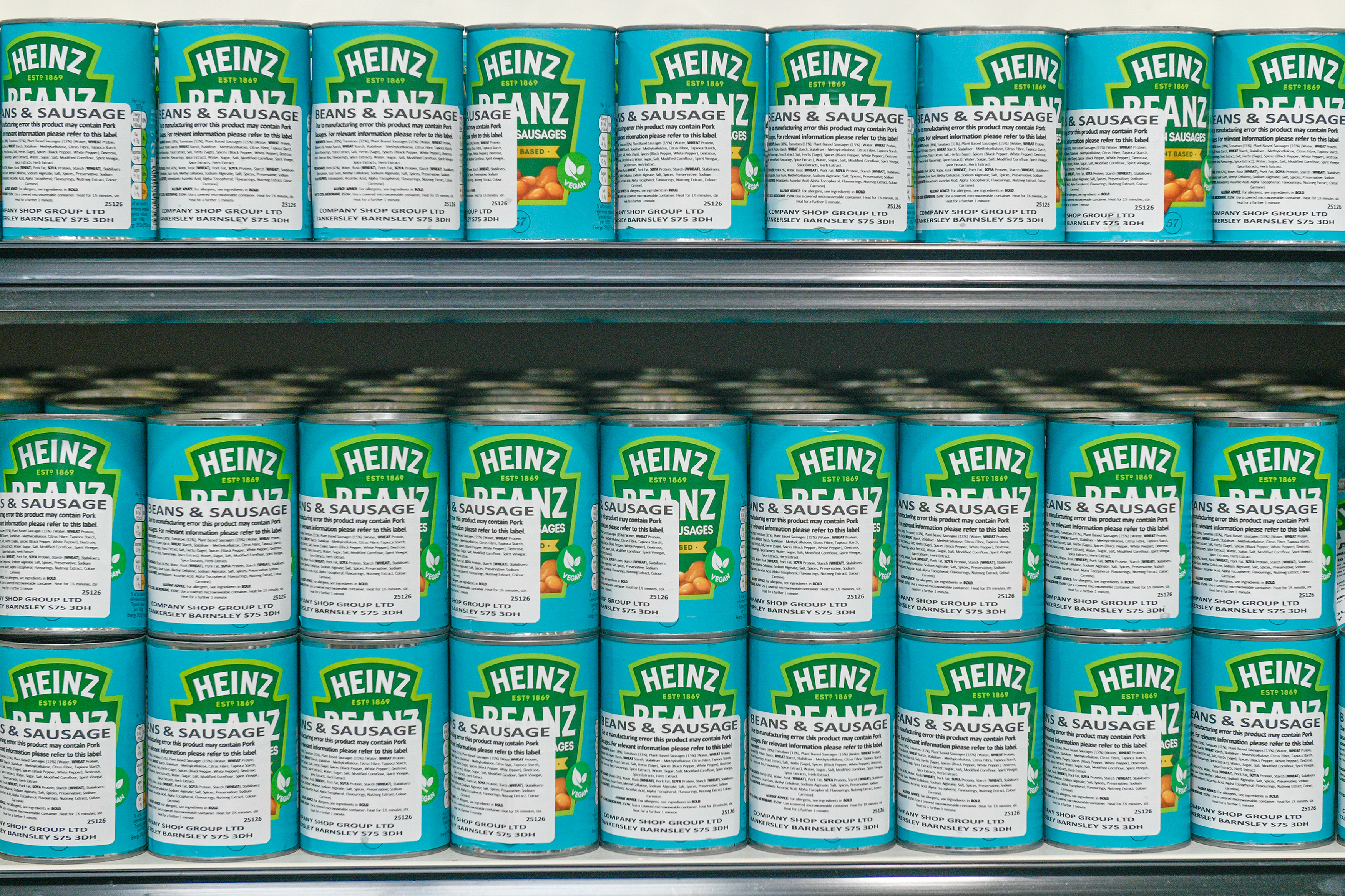 Several shelves of Heinz Beans & Sausage cans in a shop.
