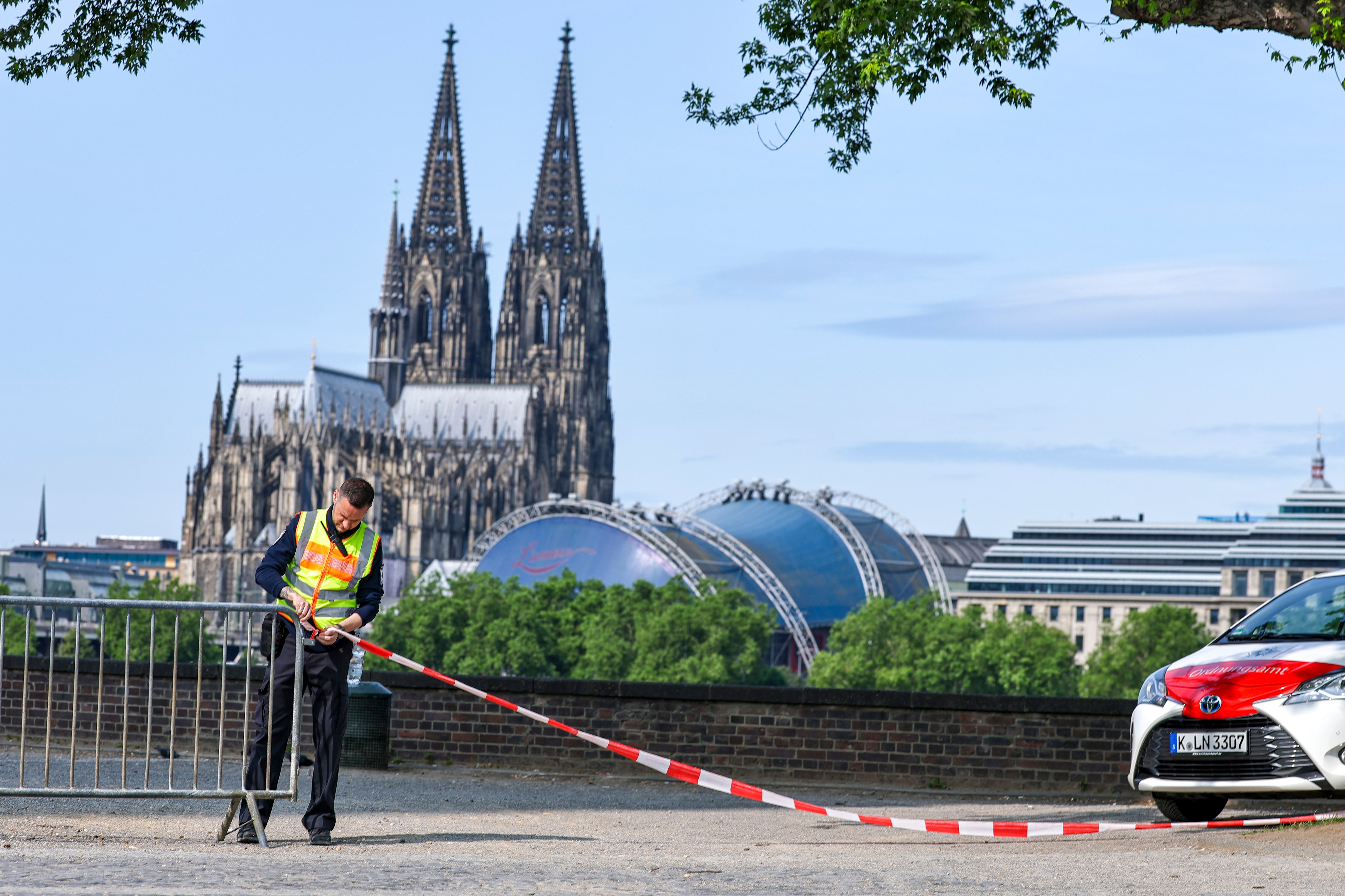 A security officer sets up a barricade in Cologne, Germany, with Cologne Cathedral in the background.