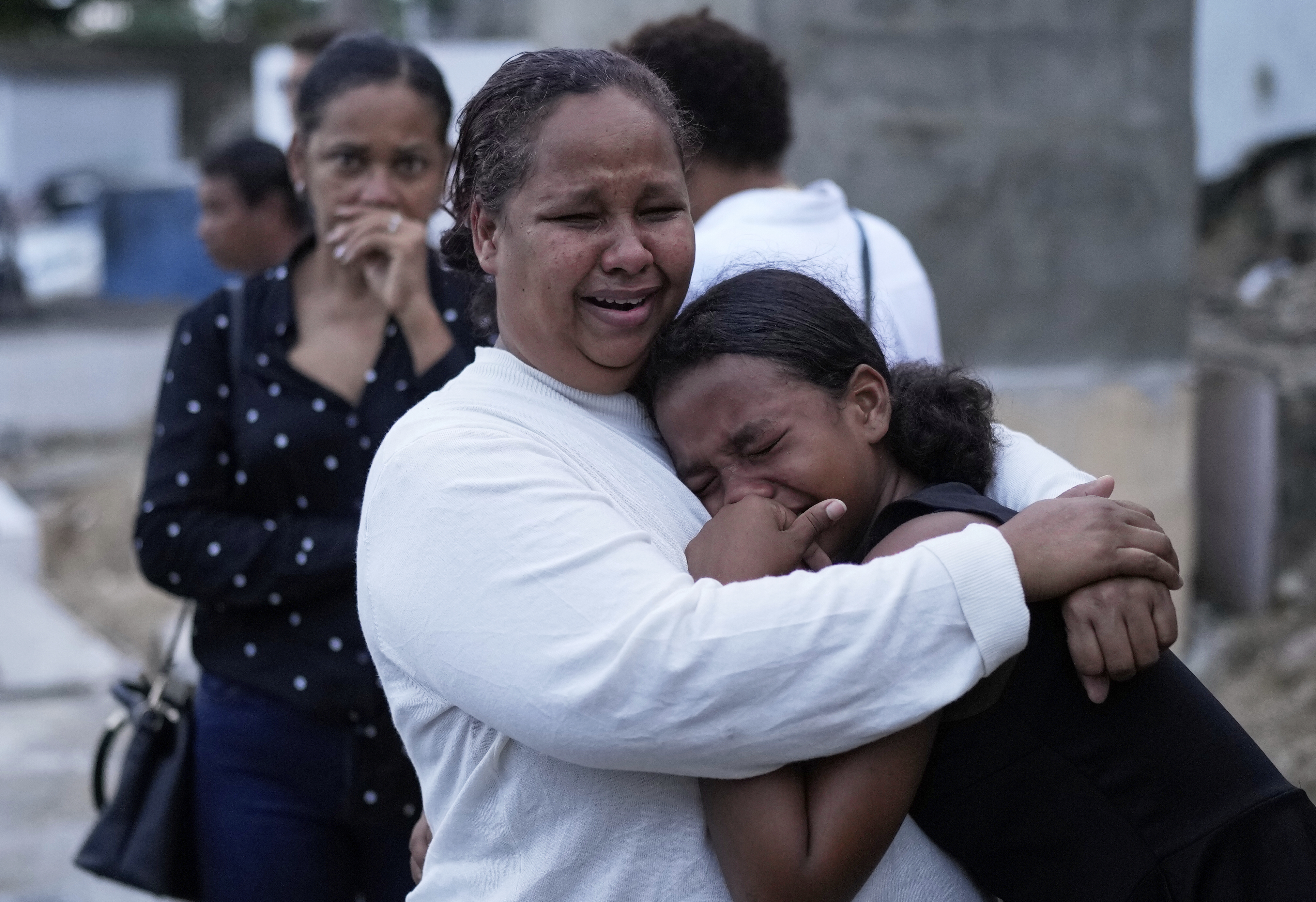 Grieving family members embrace at a funeral service.
