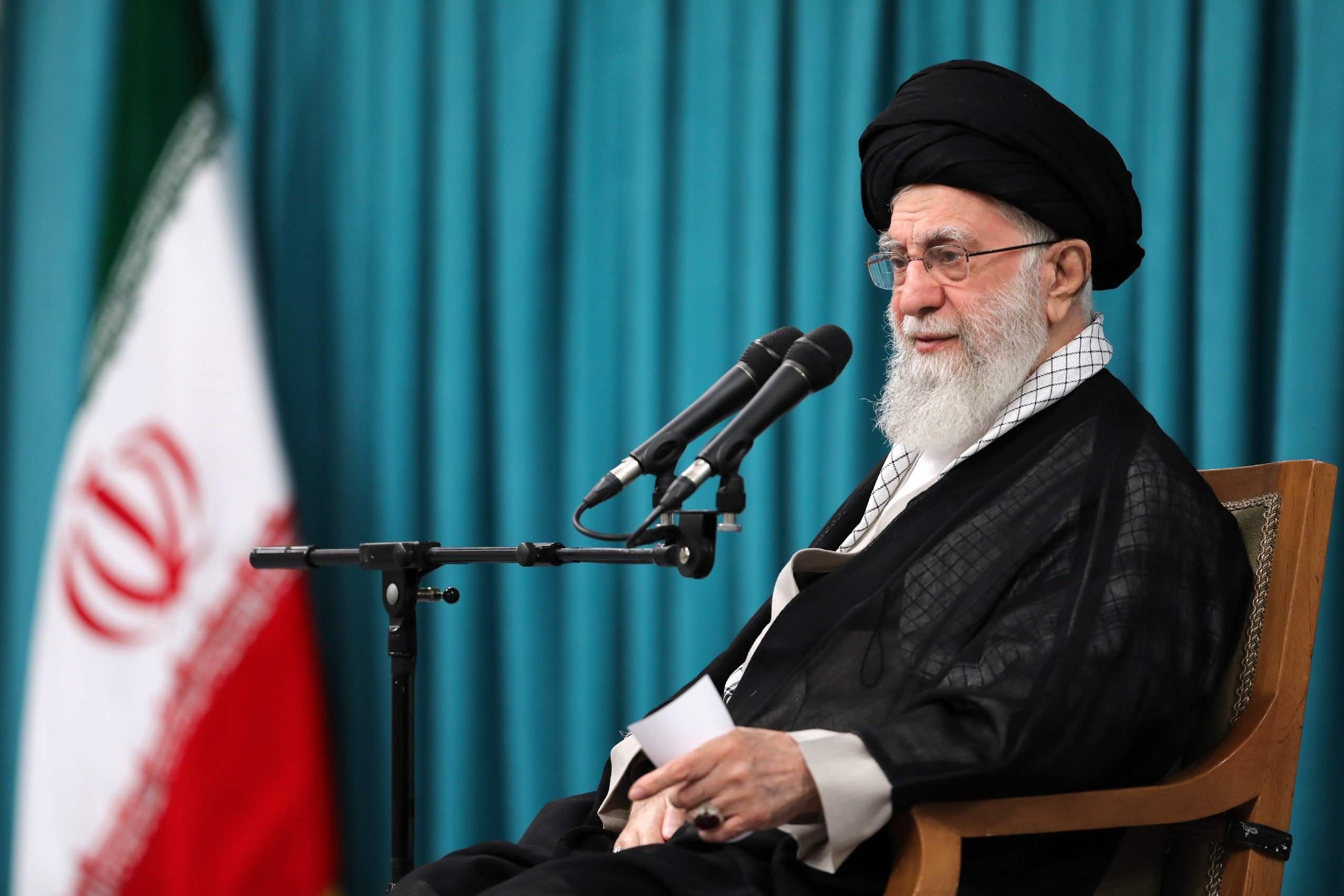 Ali Khamenei speaking at a microphone.