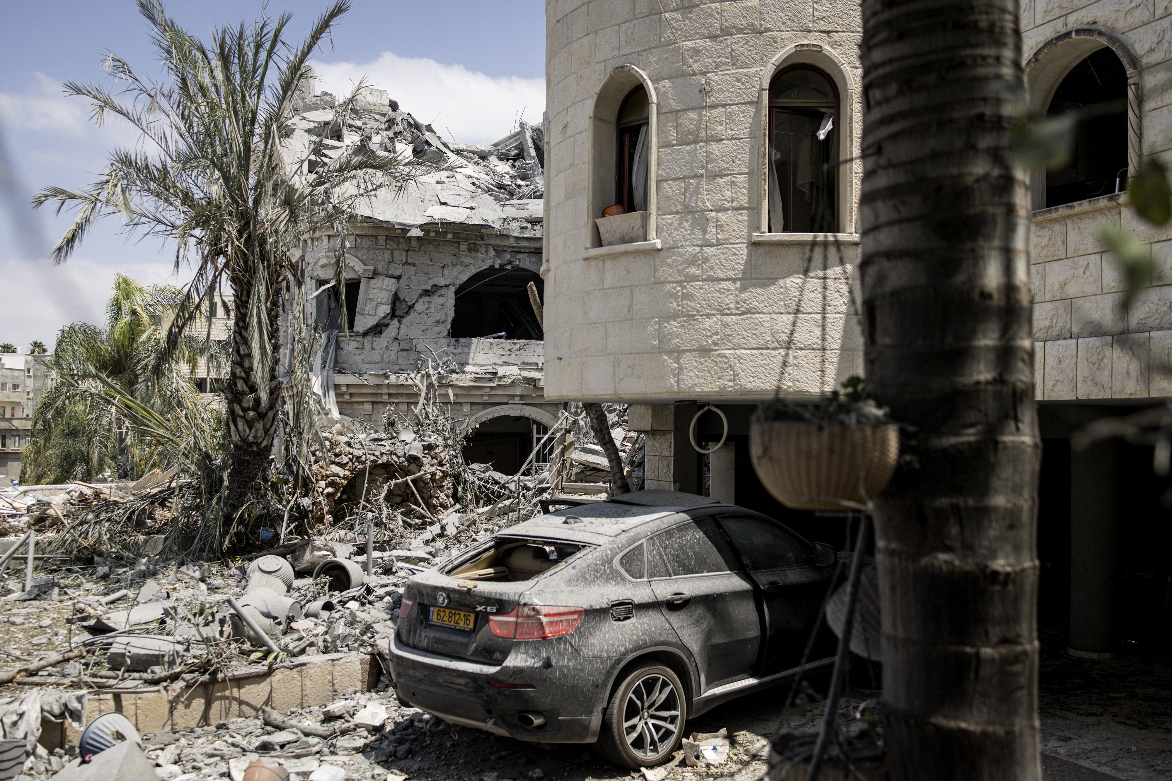 Destruction of a building and a car covered in dust after a missile attack.
