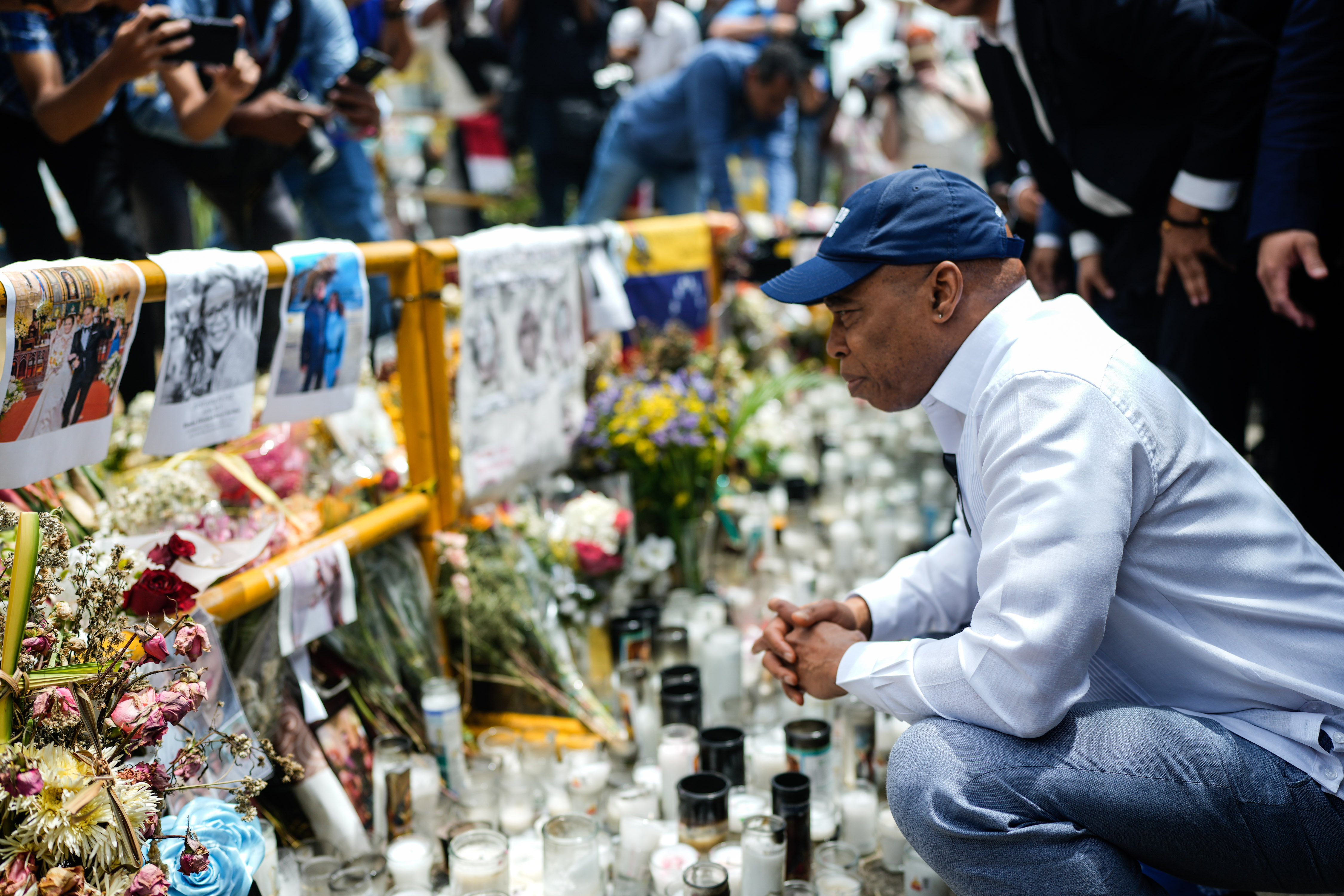 Mayor Eric Adams at a memorial with candles and flowers.