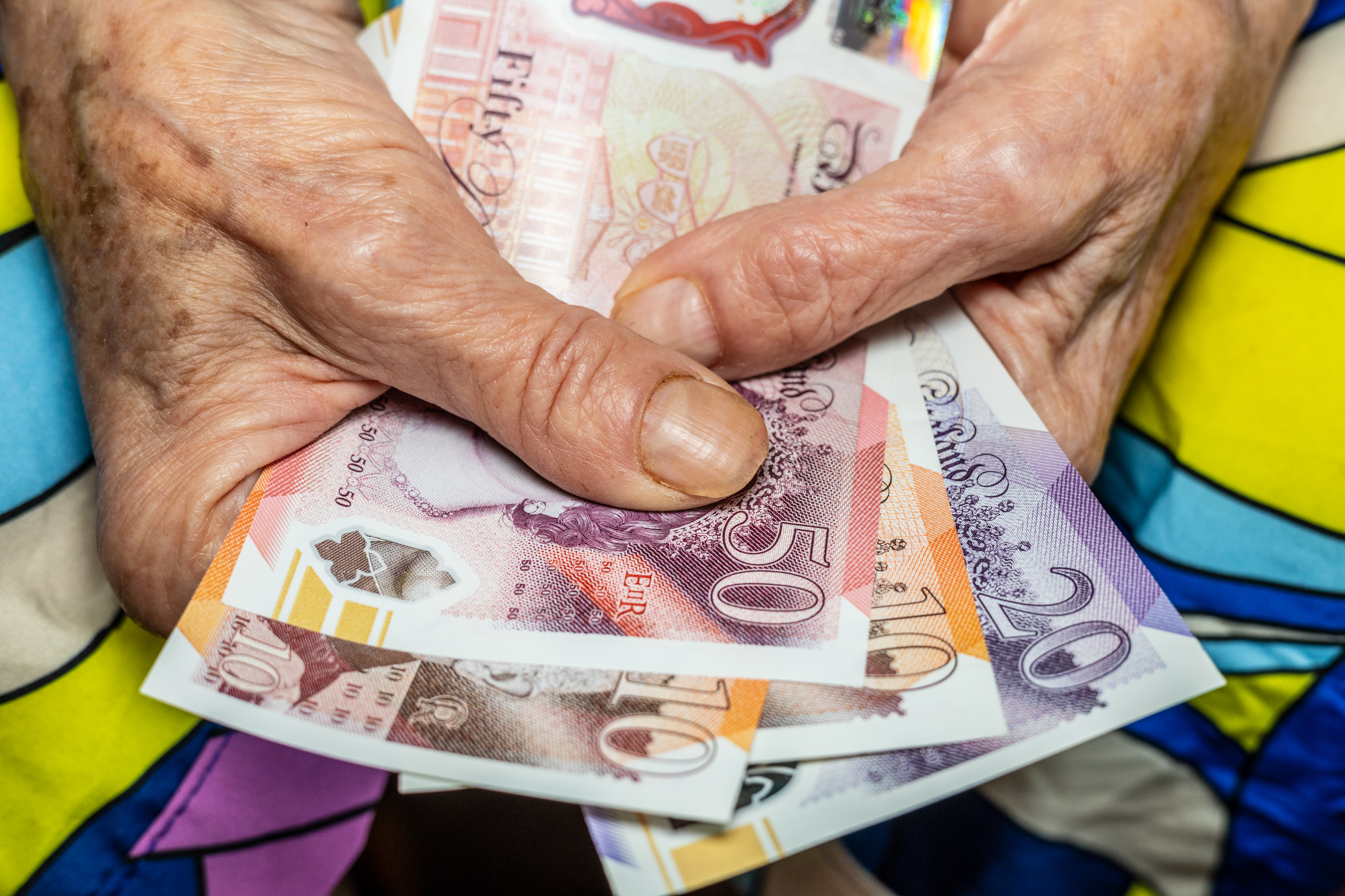 Close-up of elderly hands holding British pounds.