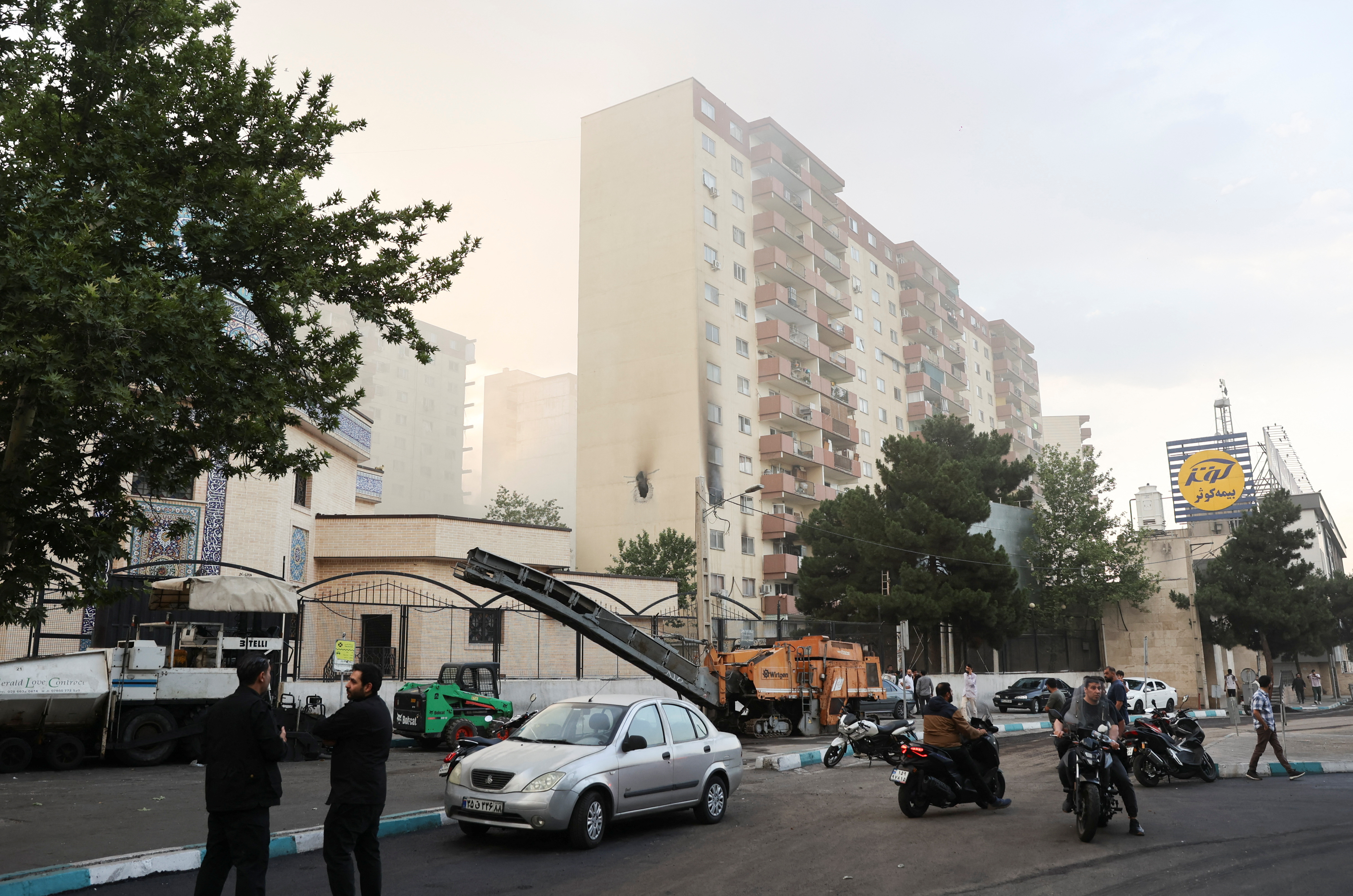 Aftermath of Israeli strikes in Tehran, showing a damaged building and people gathering.