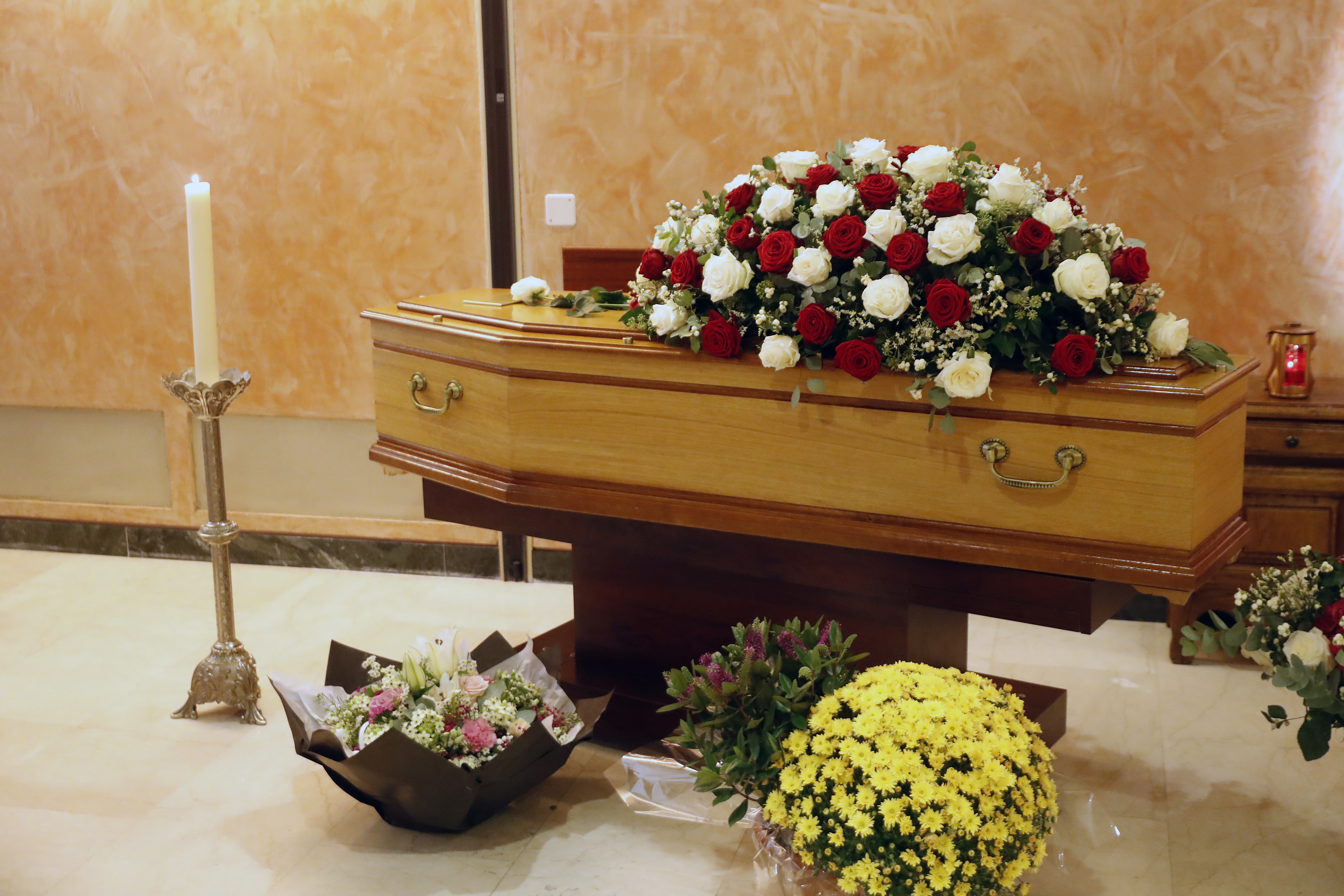 Wooden coffin adorned with red and white roses in a church.