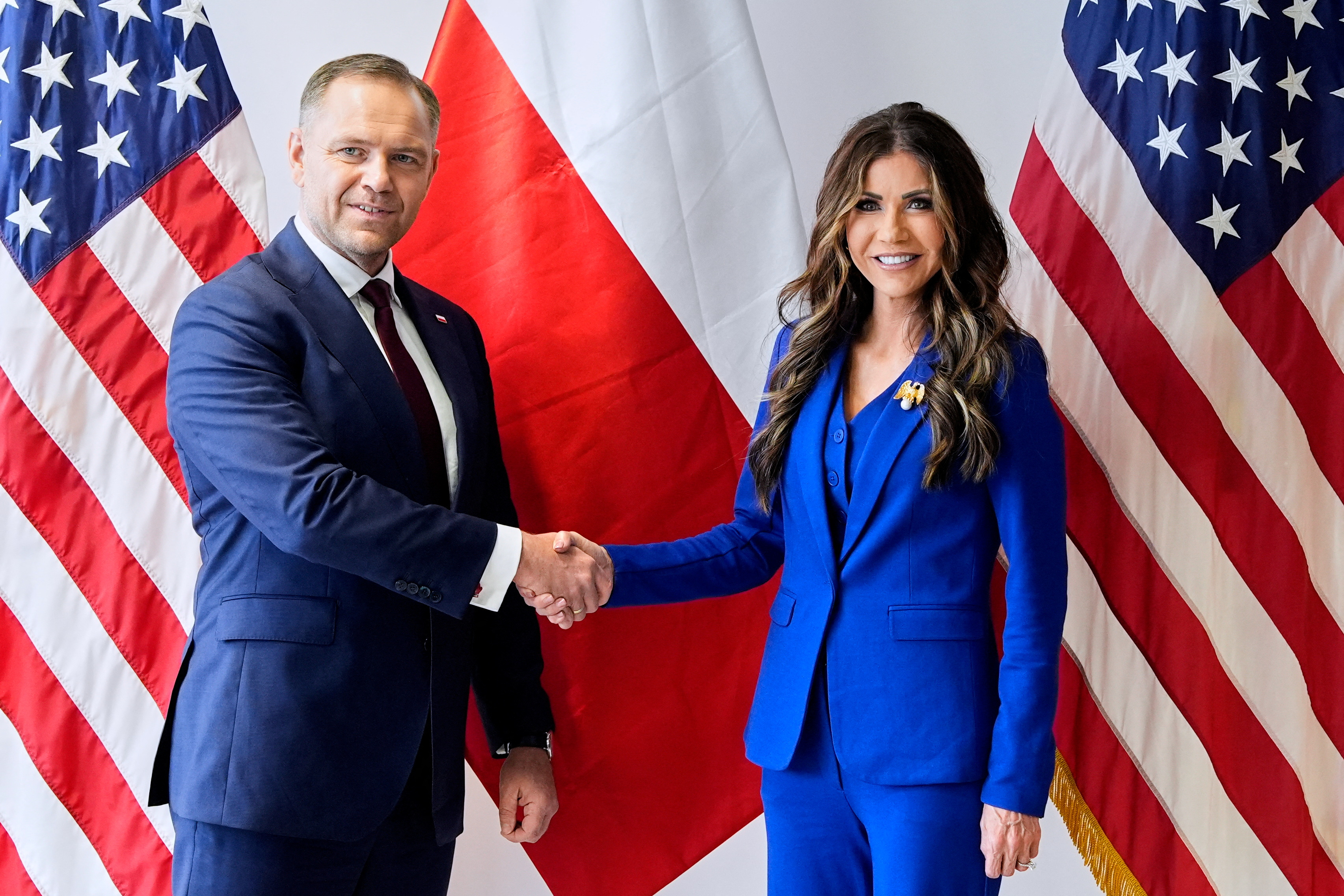 Karol Nawrocki and Kristi Noem shaking hands.
