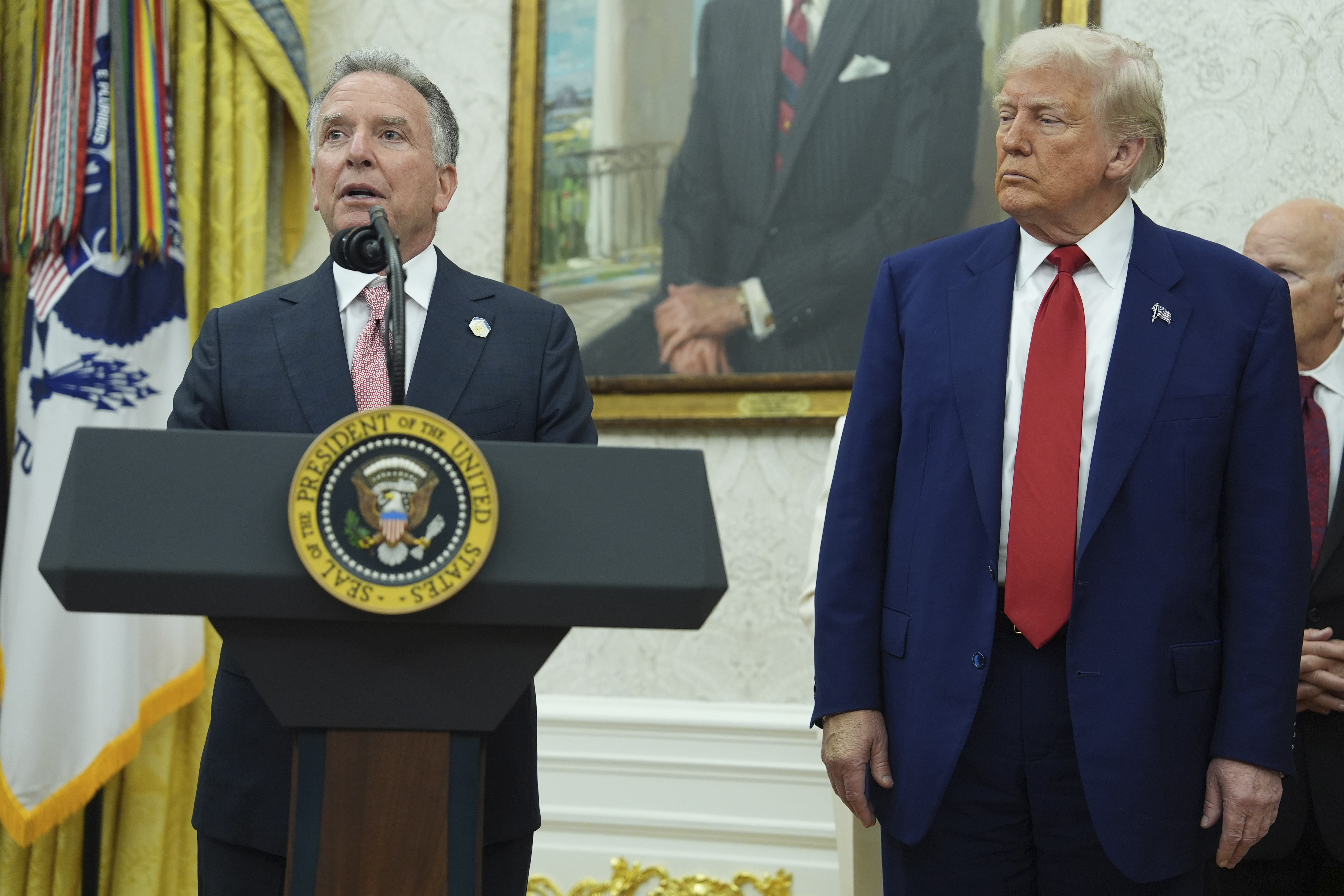 Donald Trump and another man at a podium in the Oval Office.