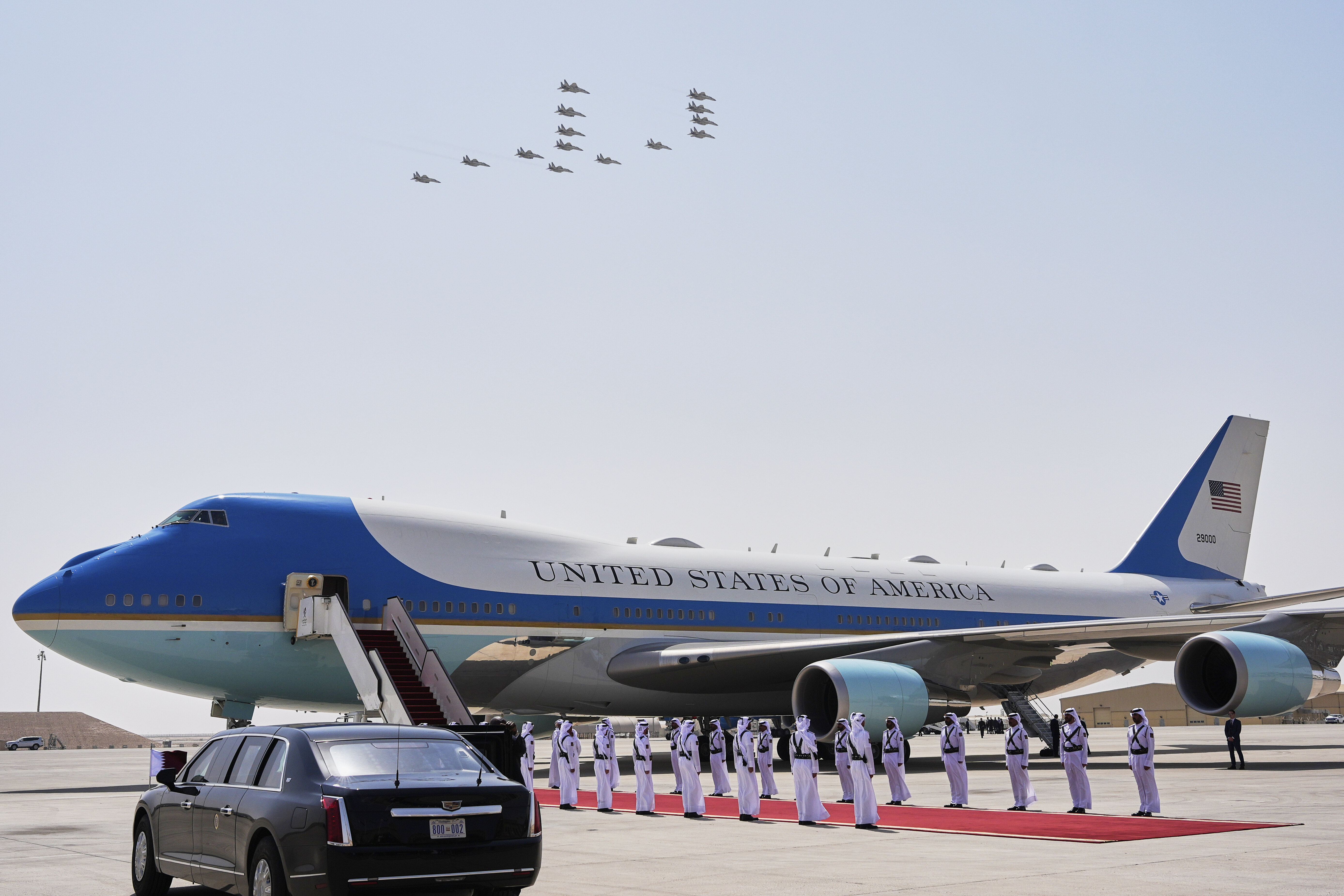 Air Force One at Al Udeid Air Base with fighter jets flying overhead.