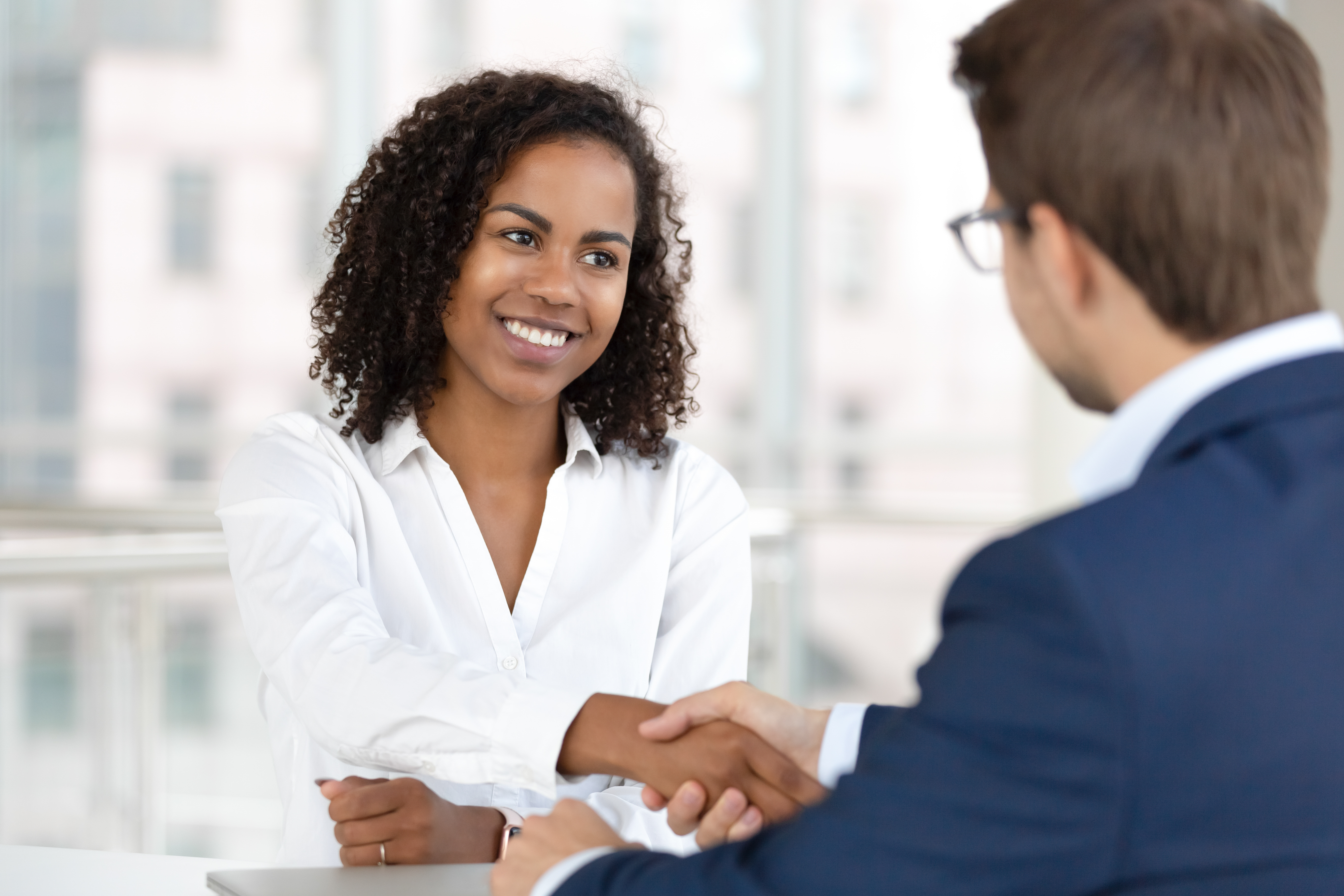 Smiling Black HR manager shaking hands with a candidate.