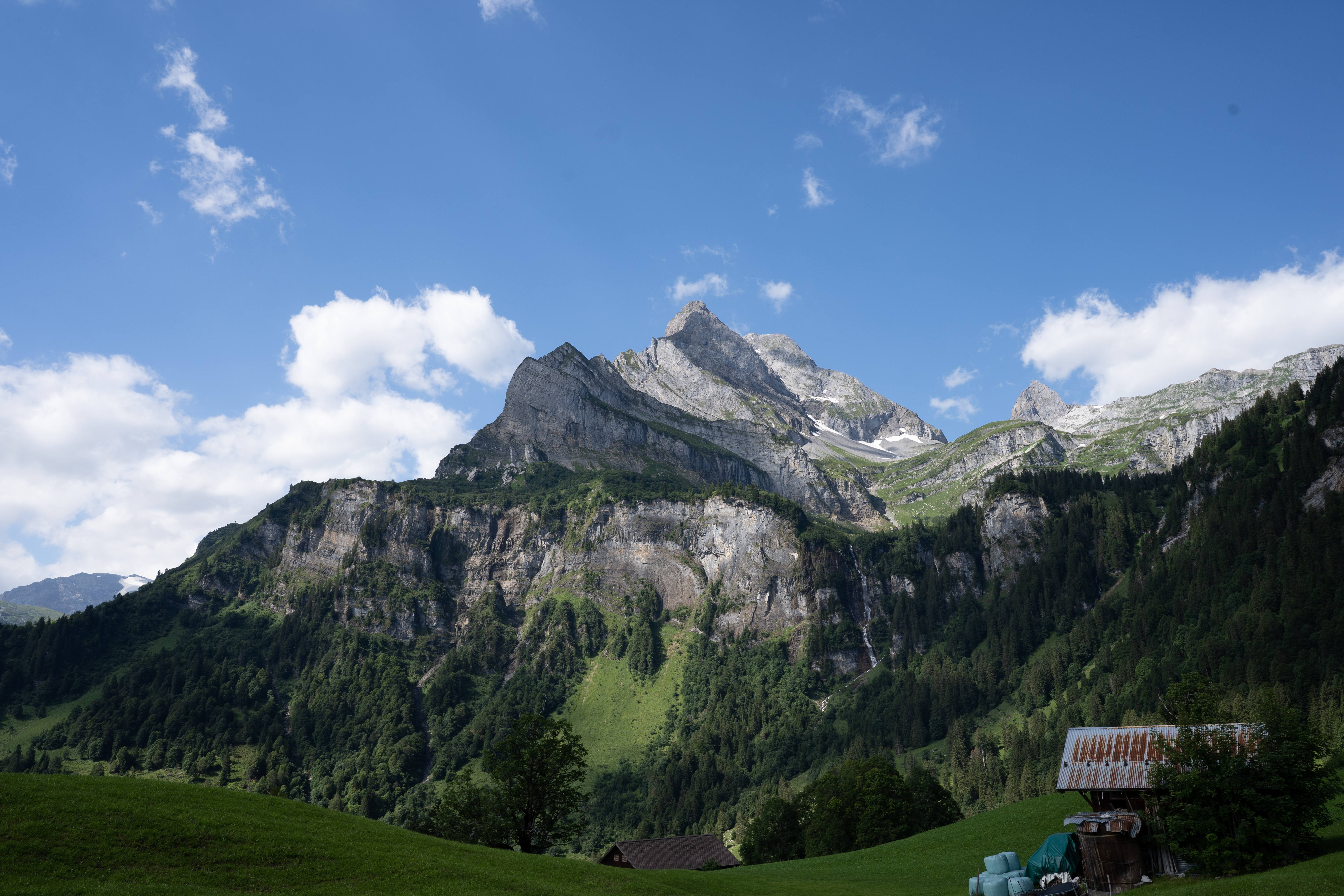 Alpine mountain range with a valley and small buildings.