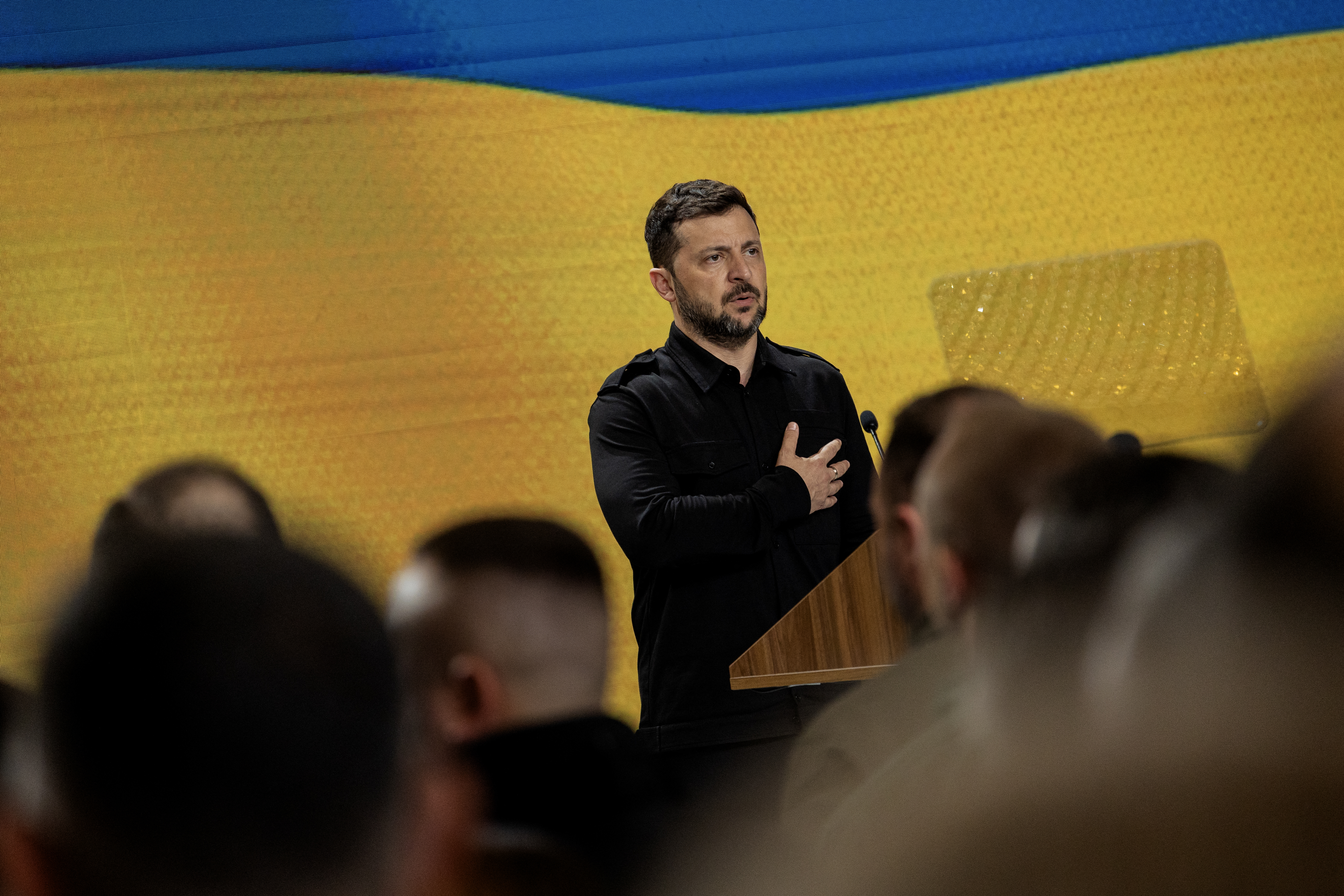 Volodymyr Zelensky speaking at a podium.