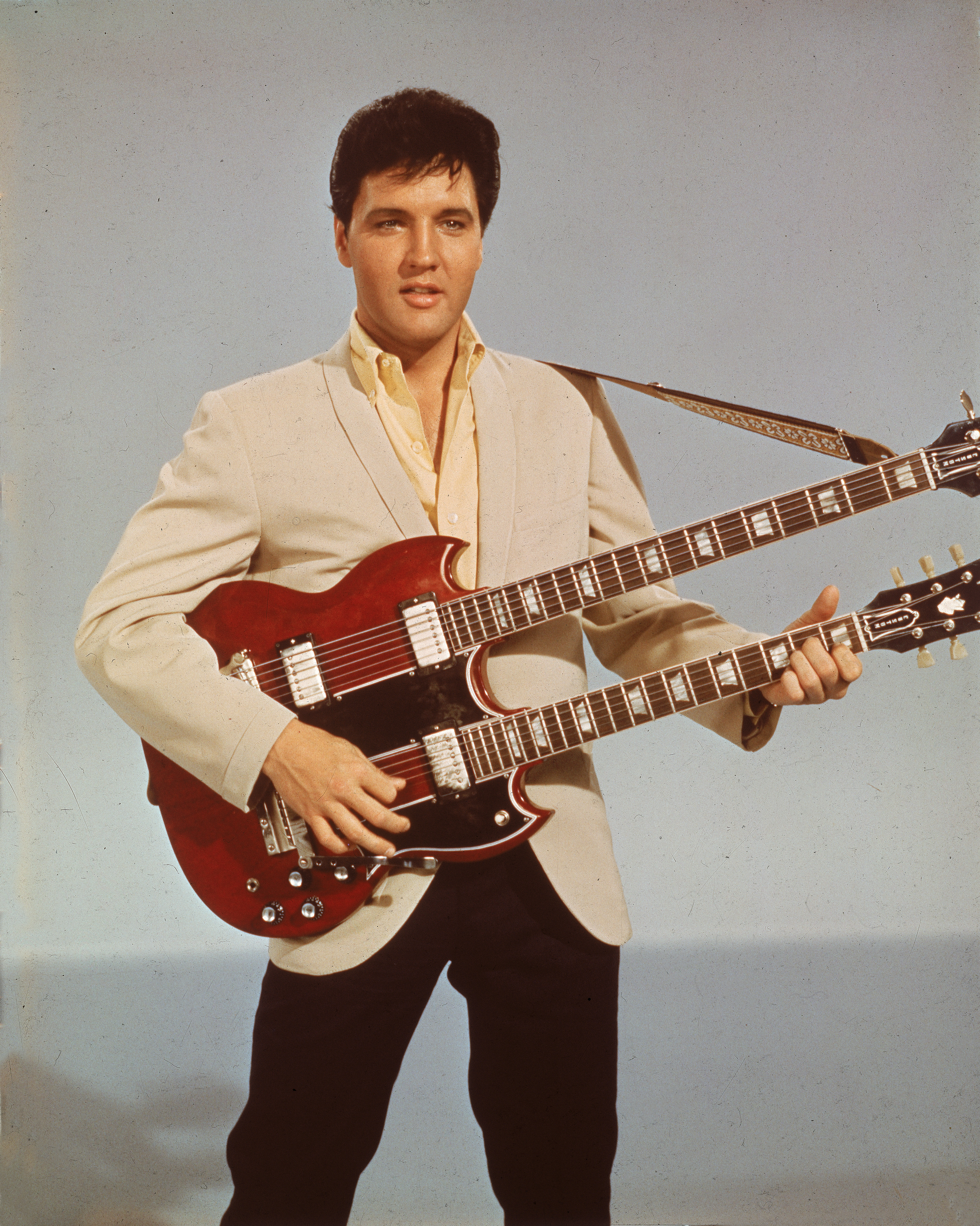 Elvis Presley playing a double-neck guitar.