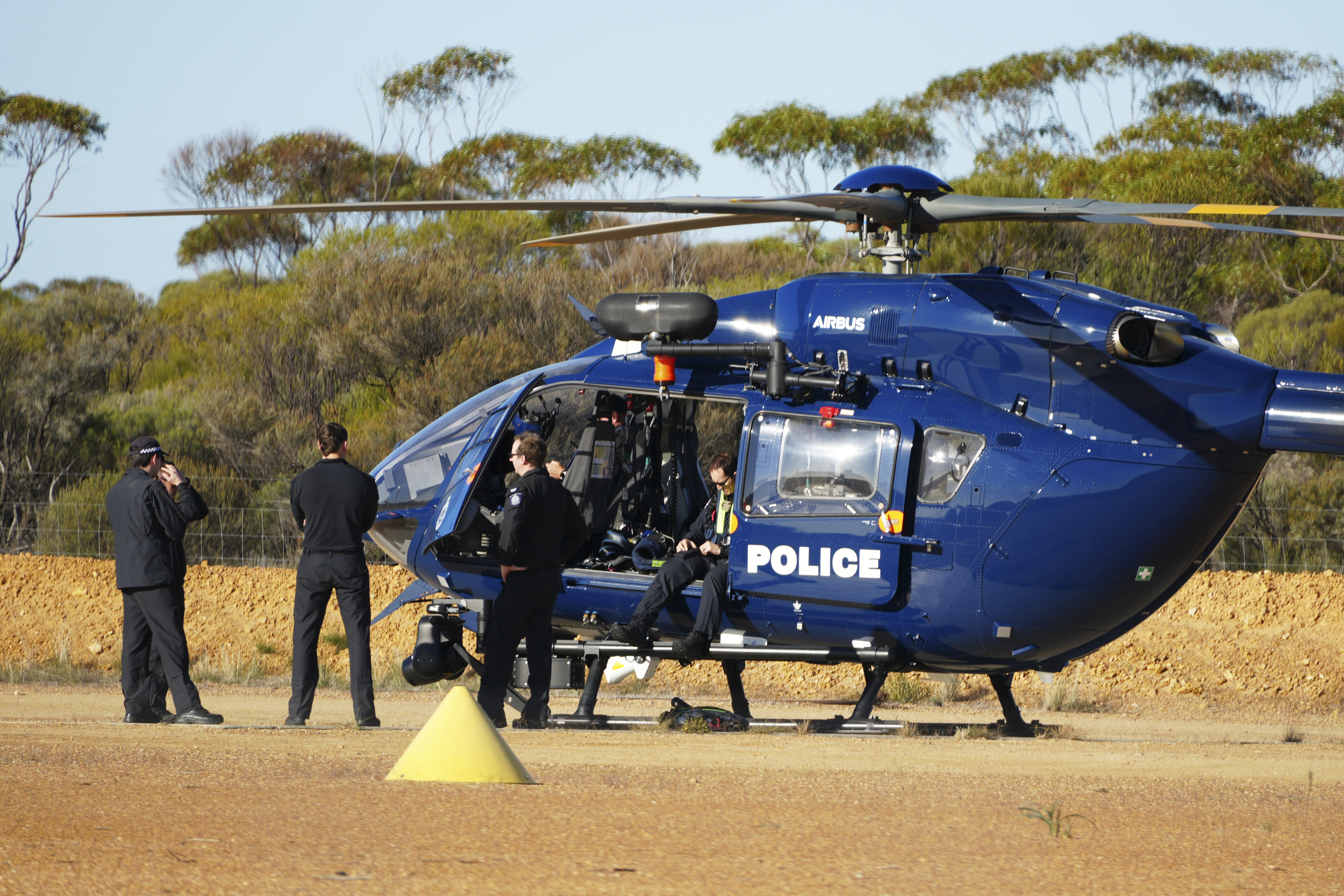 Police officers near a police helicopter.