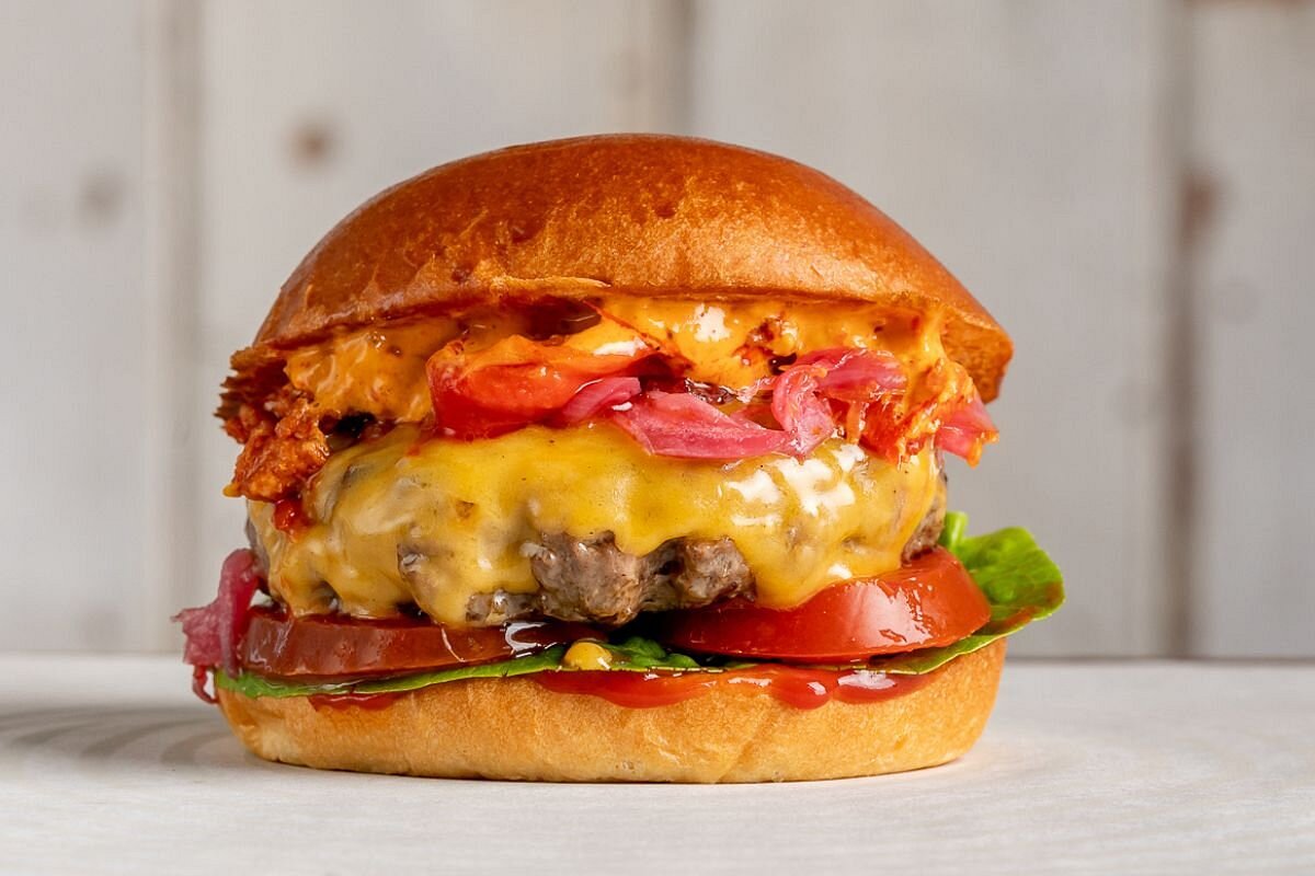 Cheeseburger with melted cheese, tomato, red onion, and sauce.
