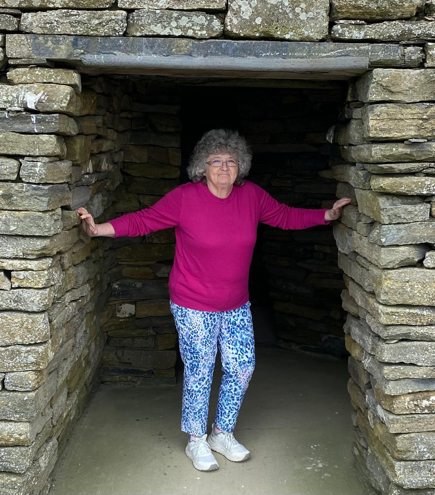 Woman standing in stone doorway.