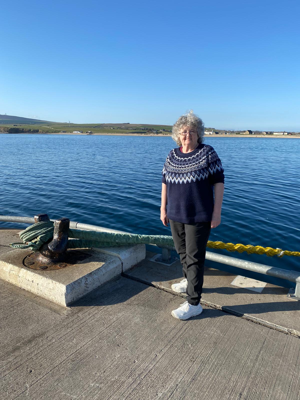 Woman standing on a dock by the water.