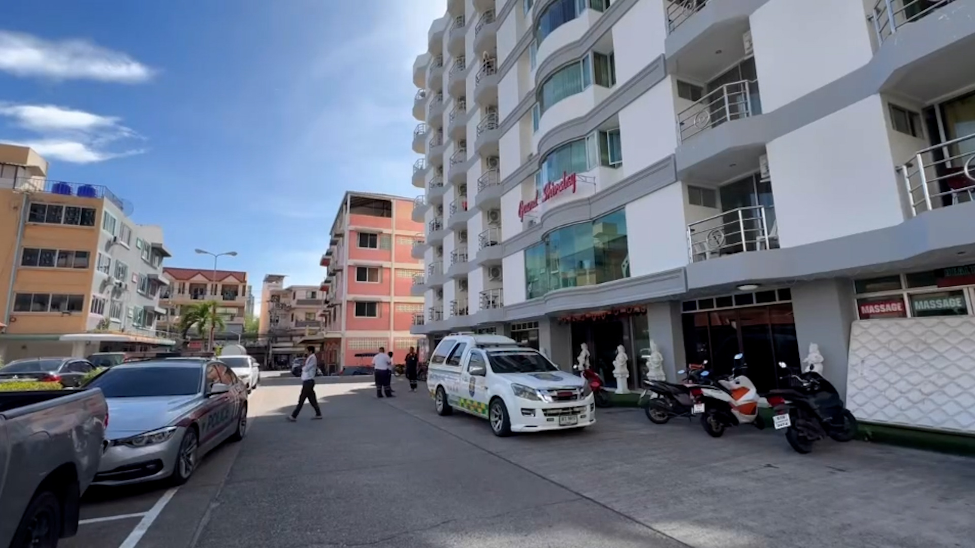 Exterior view of the Grand Shivalay apartment building in Pattaya, Thailand, with police vehicles present.