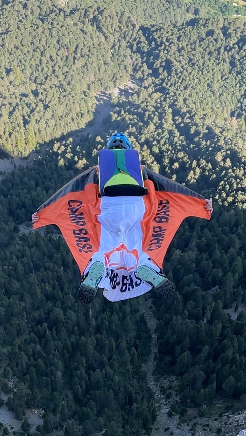 Base jumper wingsuit flying over a forest.