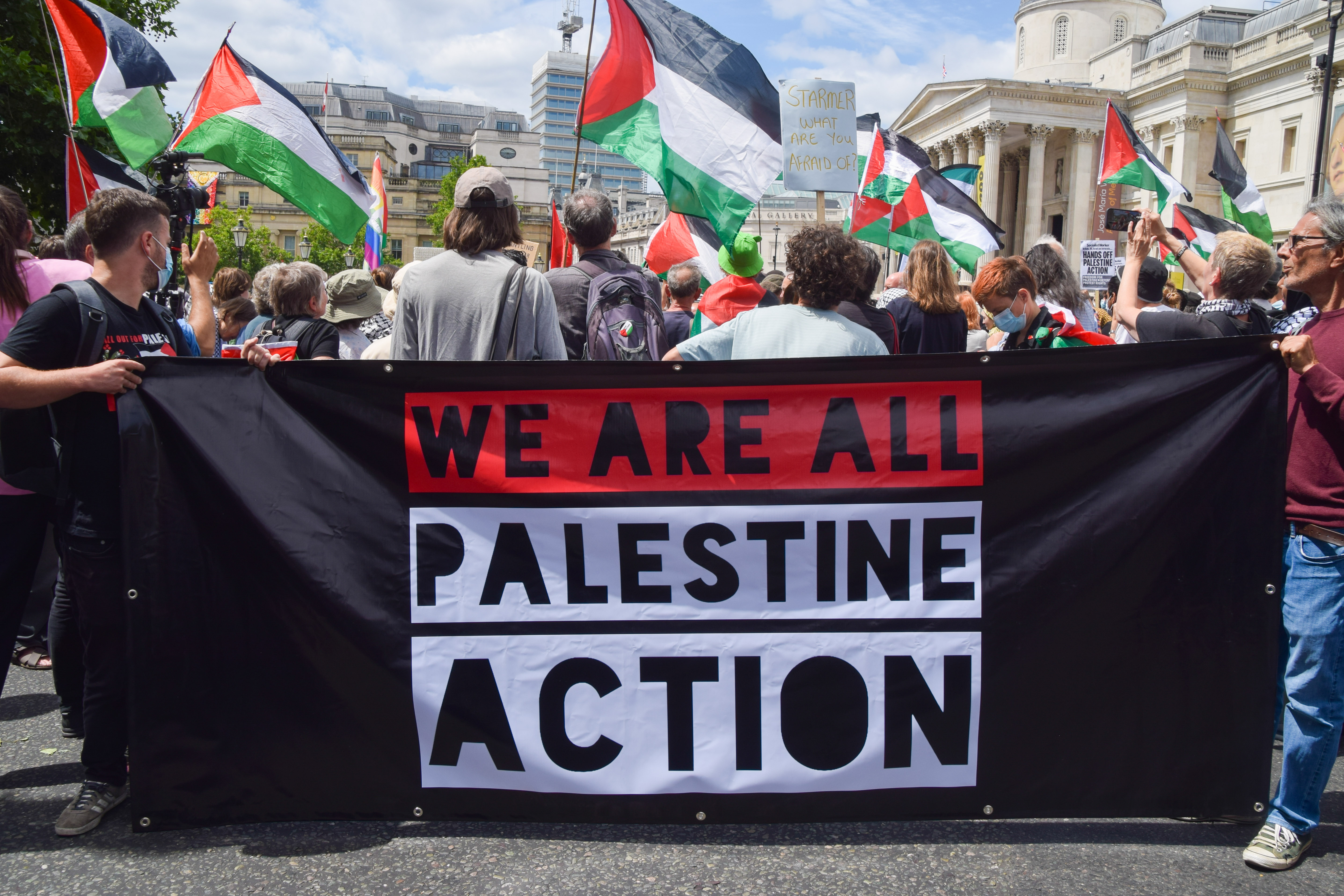 Protestors in Trafalgar Square holding a banner that reads 