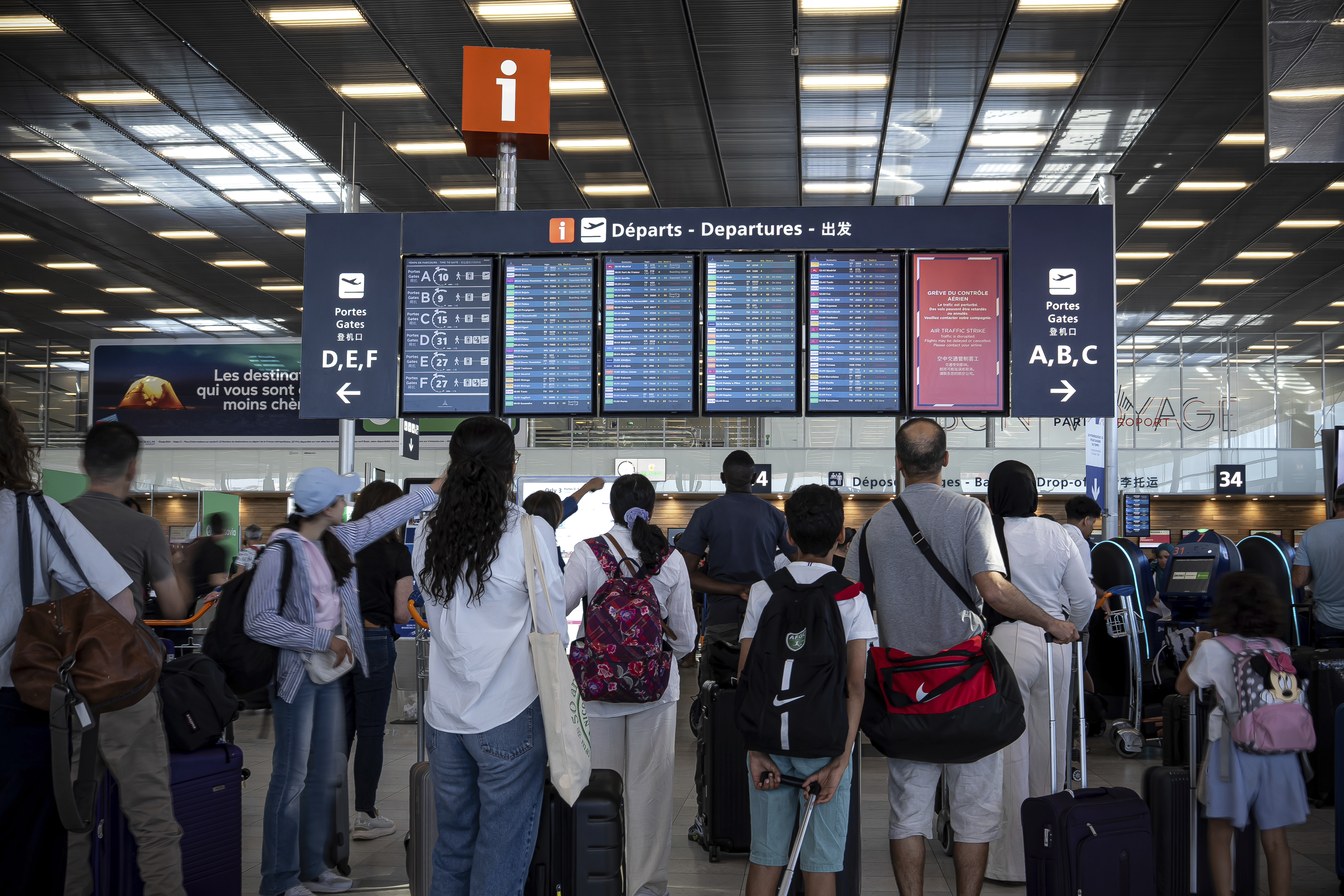 Passengers at an airport departures board during an air traffic controller strike.