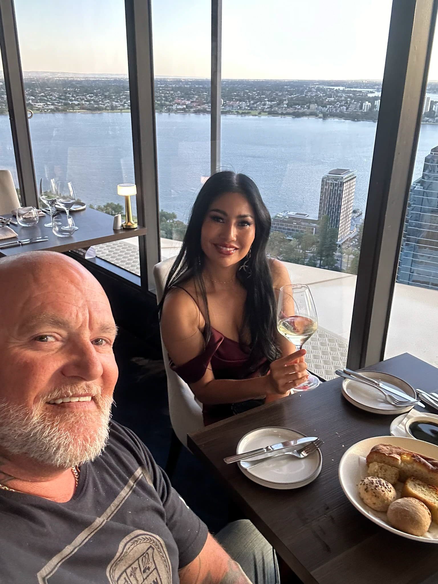 Photo of Michael Shane Caola and his wife at a restaurant with a city view.